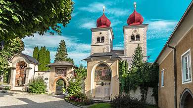 Historische Kirche mit zwei roten Zwiebeltürmen, Kapellen und begrüntem Vorplatz