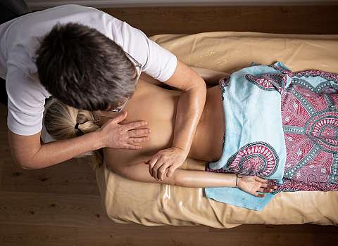 Person erhält eine Rückenmassage auf einer Behandlungsliege.