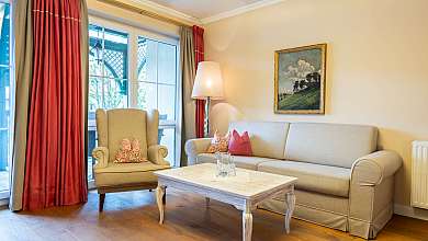Bright living room with sofa, armchair, coffee table, floor lamp and large windows.