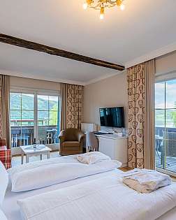 Helles Schlafzimmer mit Holzboden, Doppelbett, großen Fenstern und Garderobenschrank.