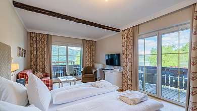 Helles Schlafzimmer mit Holzboden, Doppelbett, großen Fenstern und Garderobenschrank.