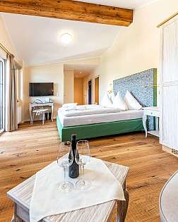 Helles Schlafzimmer mit Holzboden, Doppelbett, großen Fenstern und Garderobenschrank.