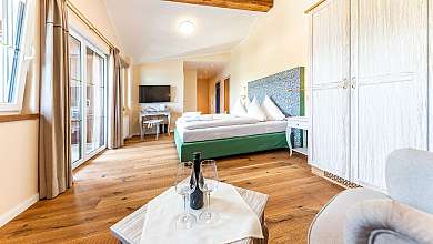 Bright bedroom with wooden floor, double bed, large windows and wardrobe.