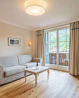 Helles Wohnzimmer mit Sofa, Couchtisch und Balkonfenstern