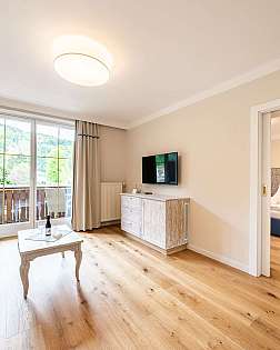 Helles Wohnzimmer mit Sofa, Couchtisch und Balkonfenstern