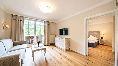 Helles Wohnzimmer mit Sofa, Couchtisch und Balkonfenstern