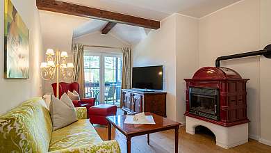 Bright living room with sofa, armchair, television, wooden table and red stove fire.